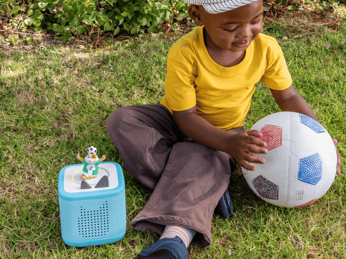 child playing with soccer ball and All-Star Animals-The Golden Whistle Games Soccer Tonie with a blue toniebox 2