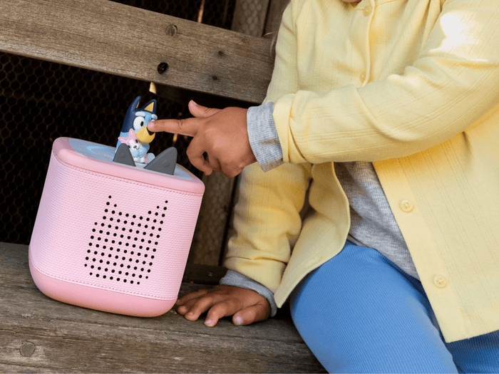 child playing with a pink toniebox 2 and a bluey tonie audio figurine for kids