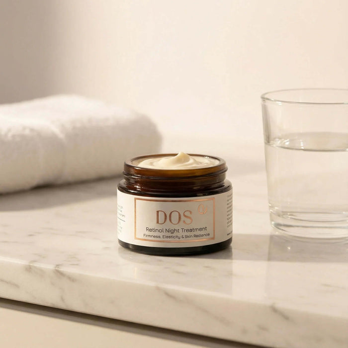 Retinol night cream in a jar on a marble countertop with a glass of water. DOS Cosmetics