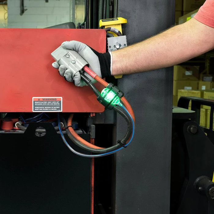 Gloved hand connecting forklift battery cable with Smart Blinky Pro battery monitor indicator