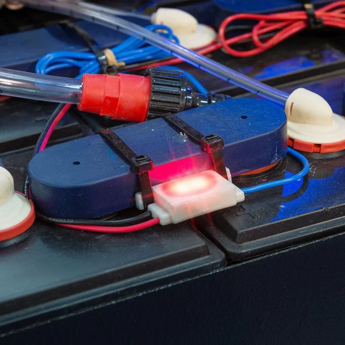Battery watering monitor with LED indicator and connected cables on a battery unit
