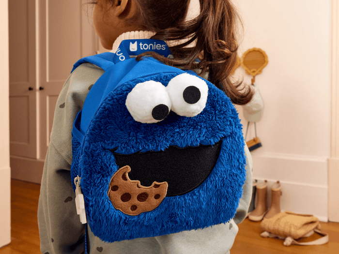 child wearing Toniebox Sesame Street Cookie Monster Backpack used to carry Toniebox, Tonies and accessories