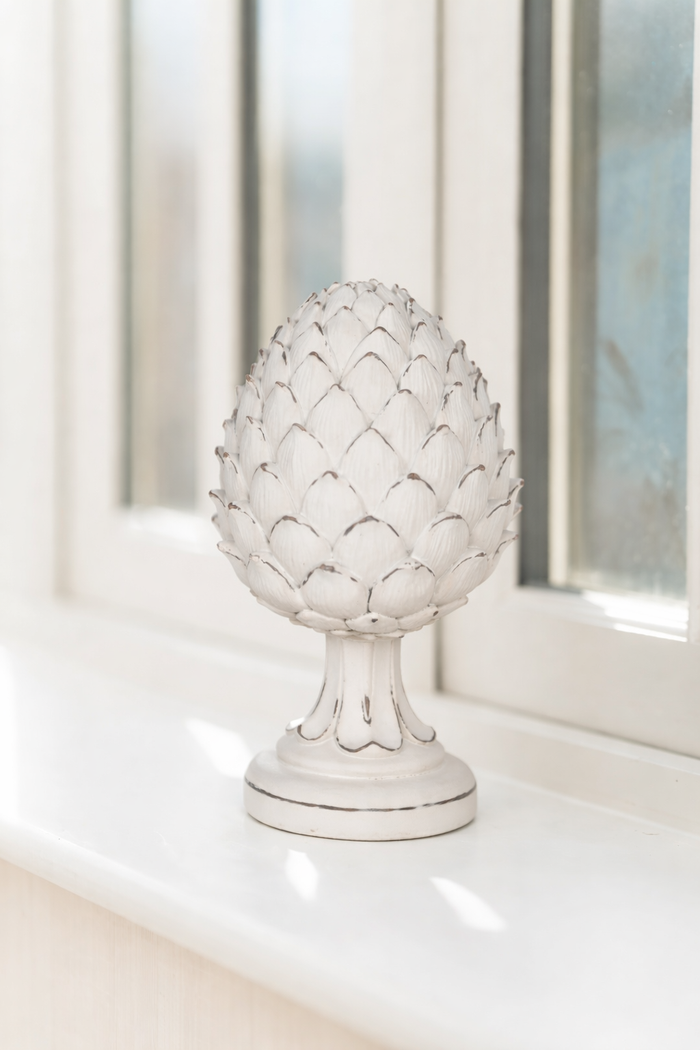 Decorative pineapple sculpture on a white surface with a blurred window background